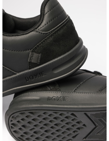 Zapatilla de cuero sintético negro con detalles sutiles, perfecta para un estilo urbano.