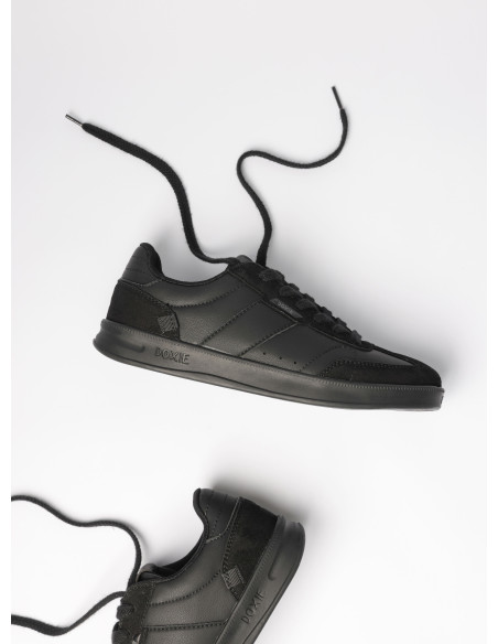 Zapatilla urbana de cuero negro que resuena con cada paso, ofreciendo estabilidad y firmeza.