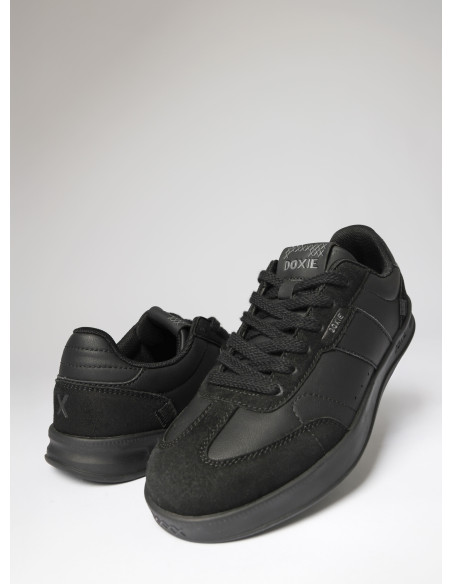 Zapatilla urbana unisex de cuero sintético negro con diseño total black y texturas oscuras.