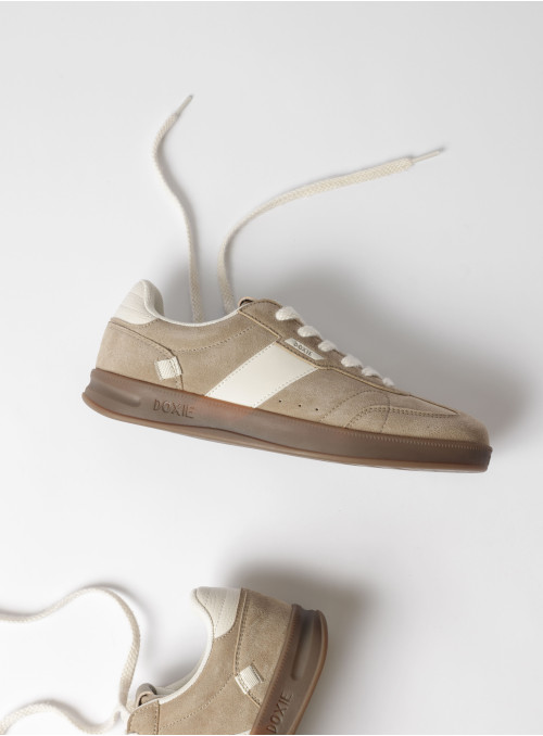 Vista lateral de zapatilla beige, mostrando su textura auténtica y diseño sencillo.