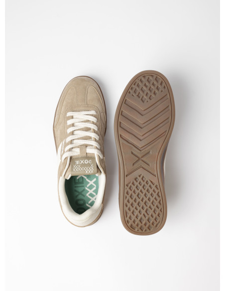 Enfoque en la parte superior de la zapatilla beige, destacando su silueta baja y estilo urbano.