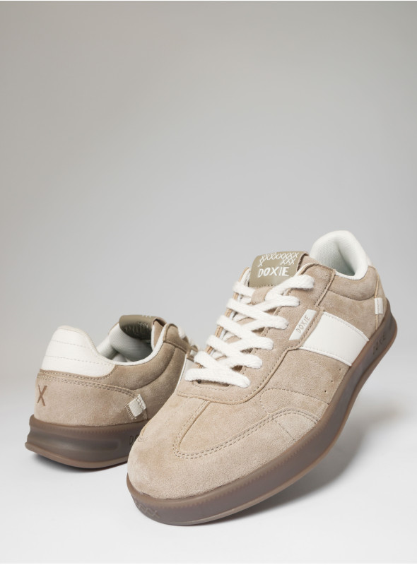 Vista lateral de zapatilla beige, mostrando su textura auténtica y diseño sencillo.