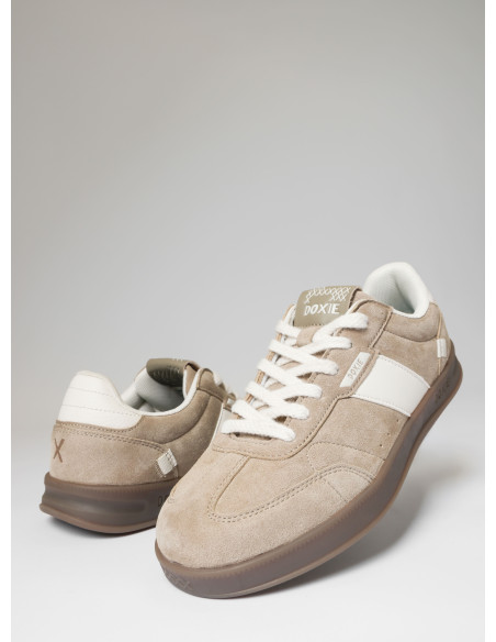 Vista lateral de zapatilla beige, mostrando su textura auténtica y diseño sencillo.