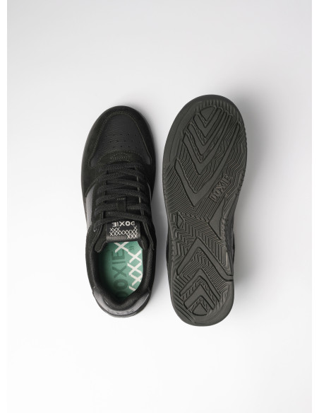 Detalle de la parte superior de la zapatilla negra, mostrando su construcción sólida y estilo urbano unisex.