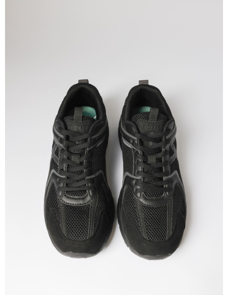 Zapatilla negra unisex con suela estable, diseñada para largas jornadas de movimiento.