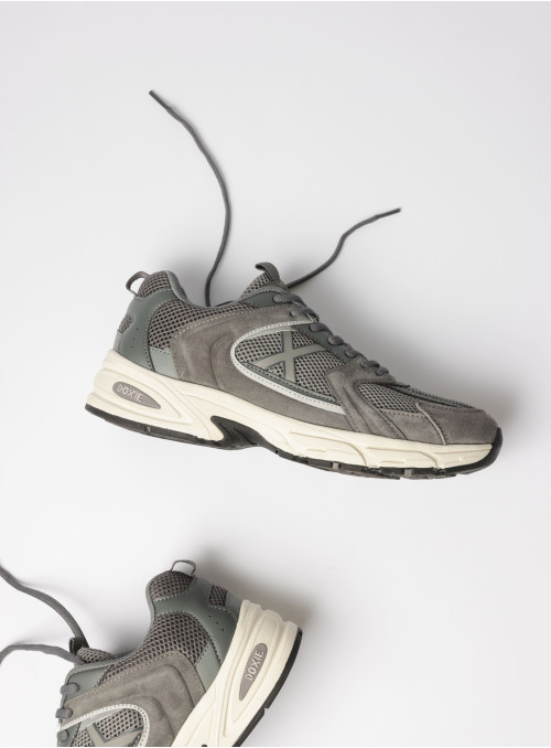 Vista lateral de zapatilla gris unisex, con detalles en cuero y textil, perfecta para el día a día.