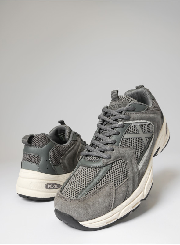 Vista lateral de zapatilla gris unisex, con detalles en cuero y textil, perfecta para el día a día.