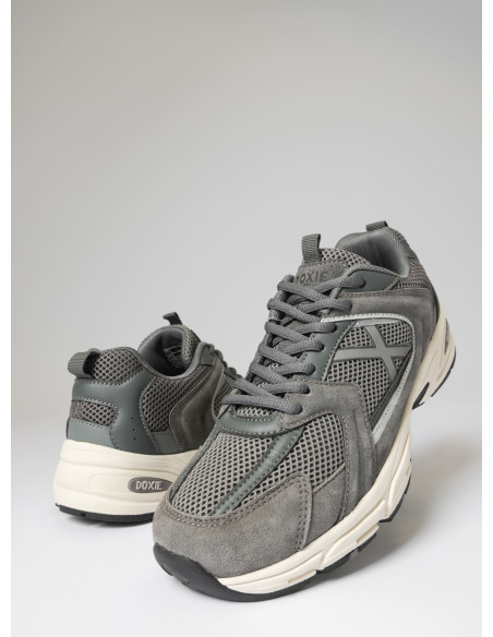 Vista lateral de zapatilla gris unisex, con detalles en cuero y textil, perfecta para el día a día.