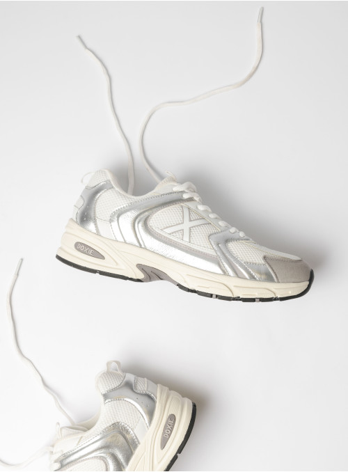 Vista lateral de zapatilla unisex plata con diseño retro-futurista, perfecta para el estilo urbano.