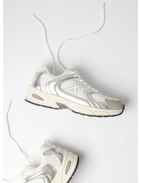 Zapatilla urbana de cuero y textil en plata, muestra de su brillo y volúmenes dinámicos.