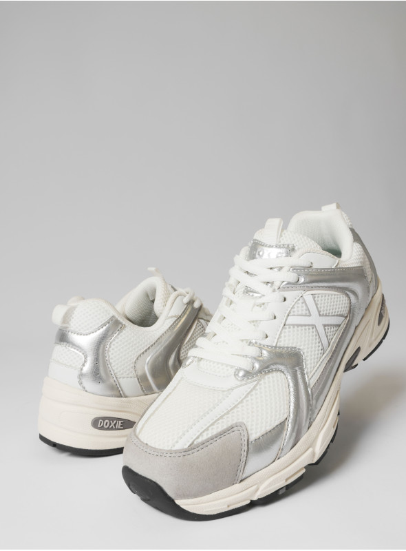 Vista lateral de zapatilla unisex plata con diseño retro-futurista, perfecta para el estilo urbano.