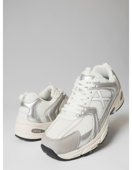 Vista lateral de zapatilla unisex plata con diseño retro-futurista, perfecta para el estilo urbano.